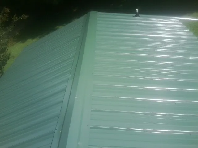 New green metal panels meeting at the ridge of a roof — Flat Roof Repair work by our crew in Kirkville