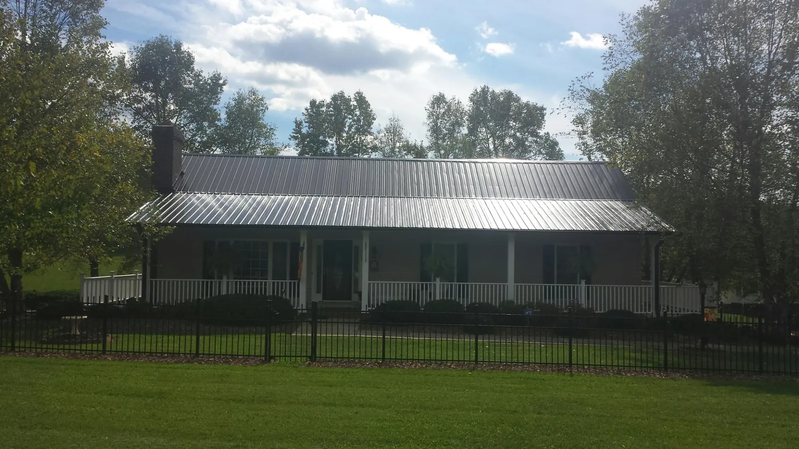 Gray metal roof on a brick ranch with a full width front porch — Gutter Guard Installation work by our crew in Kirkville