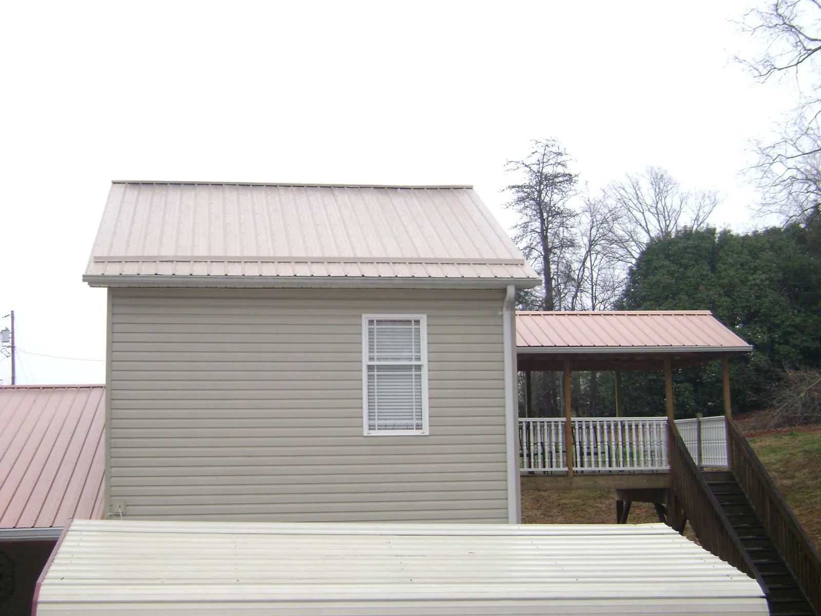 Tan metal roofs on a two story addition and attached porch, from a Roof Replacement job in Kirkville